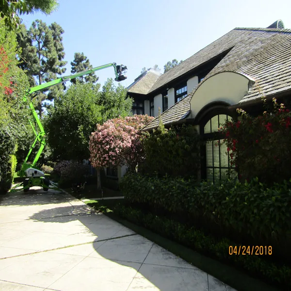 Lift-assisted roof access beside a landscaped home used to illustrate hillside and gated-access planning.